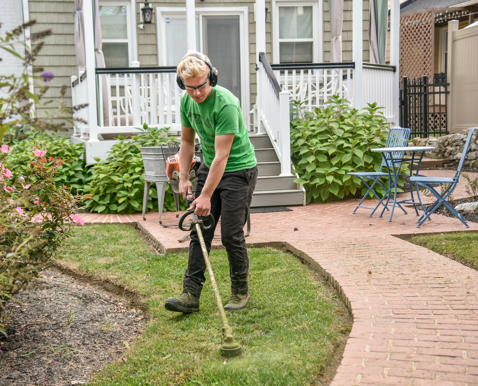 Crew member edging a lawn along a brick walkway
