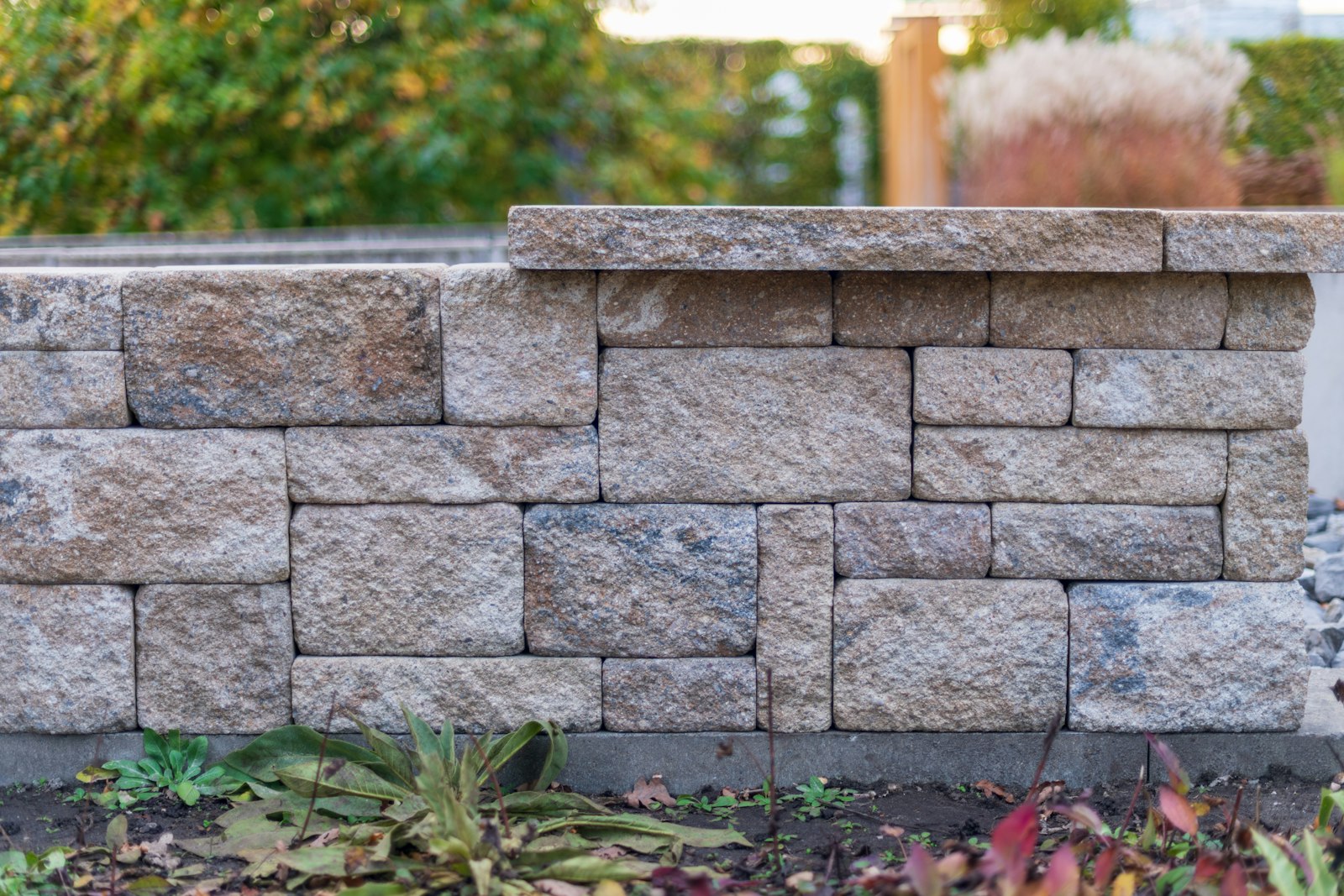 Segmental stone retaining wall with capstone in a garden bed